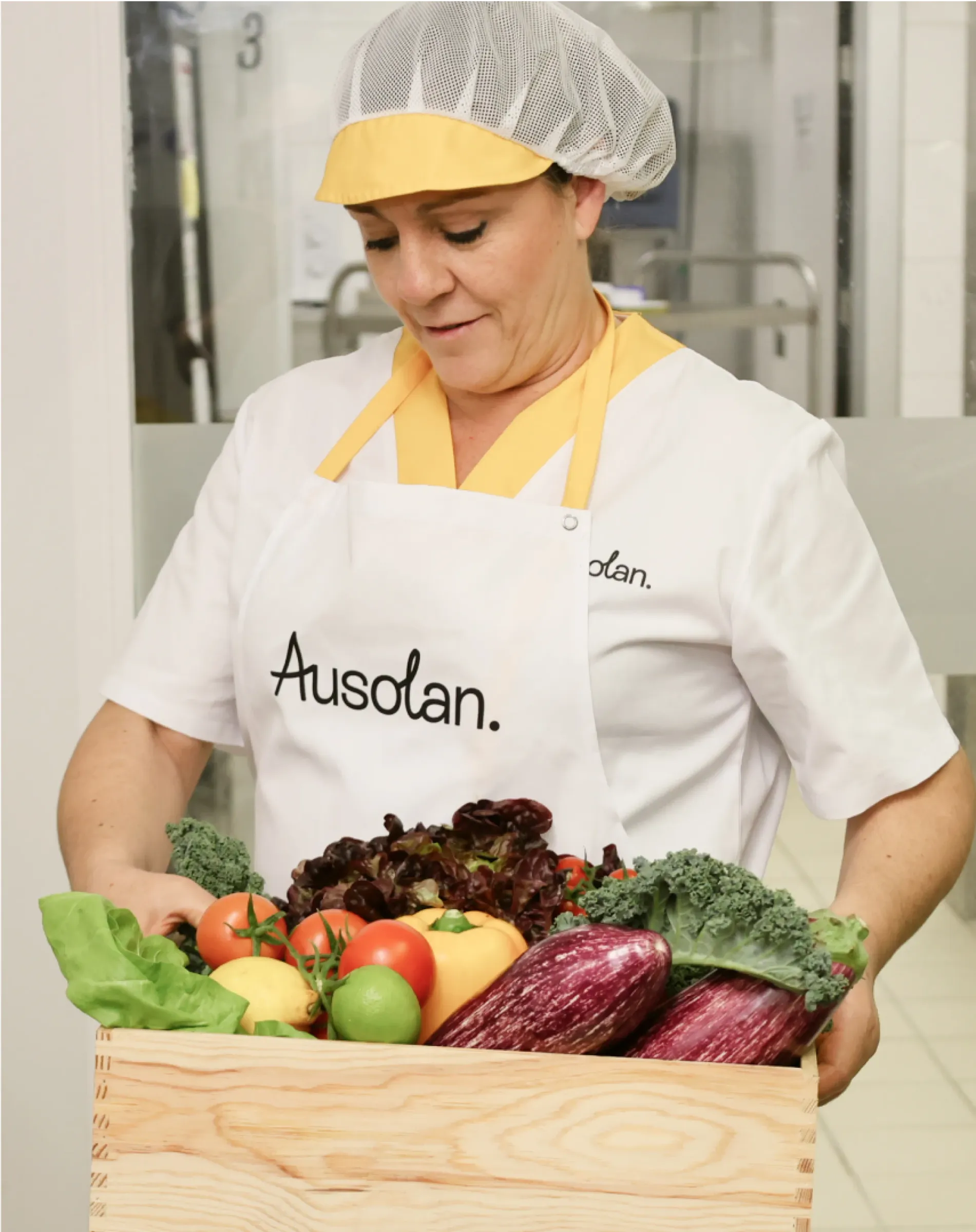 Mujer con uniforme de Ausolan y caja de verduras