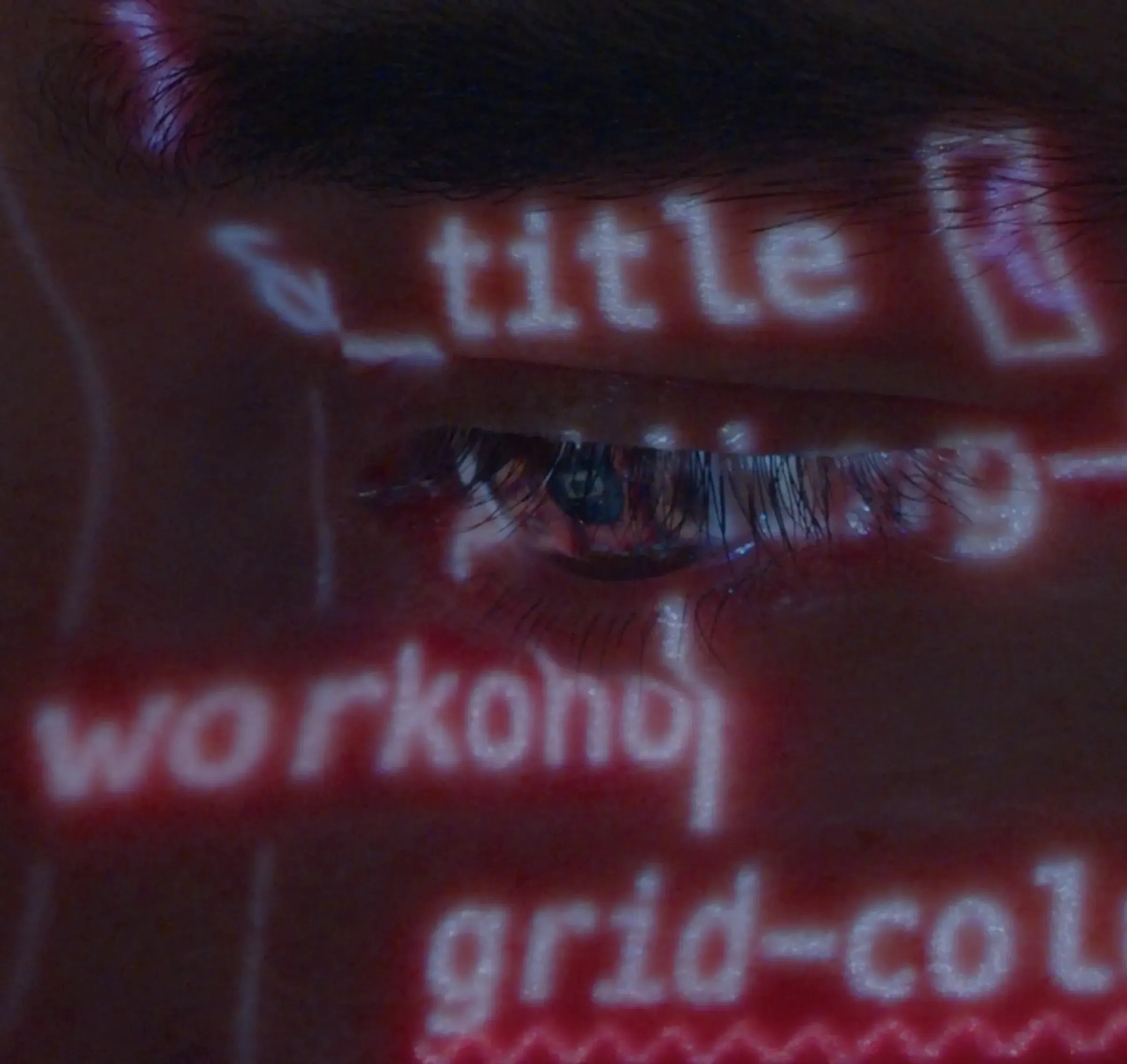 Primer plano de un ojo con código del sistema de diseño de Workoholics proyectado sobre la piel en luz rosa.